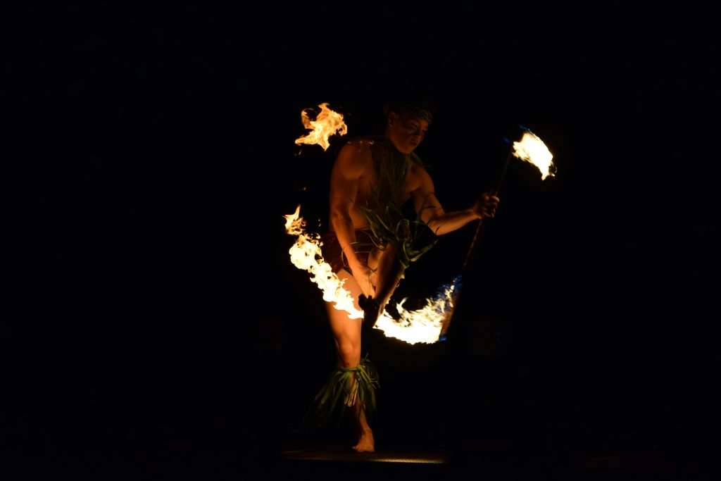 A captivating fire dancer performing a traditional Hawaiian dance at night.