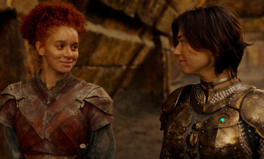 image shows two women looking at each other lovingly. They are both wearing armor.